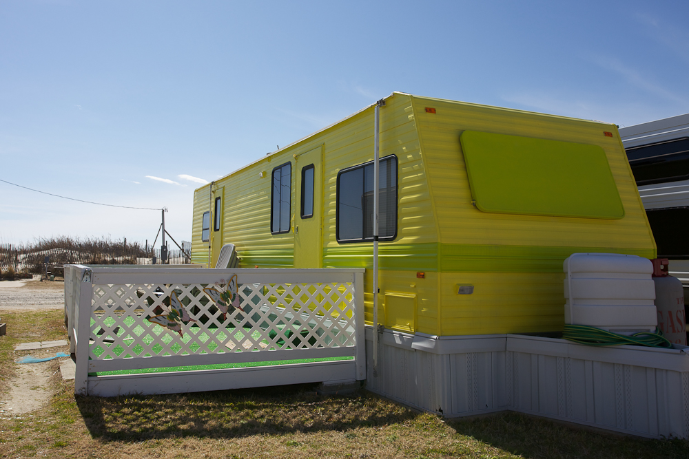Lattice deck and butterfly tchotchkes decorate the deck of this colorfully painted travel trailer